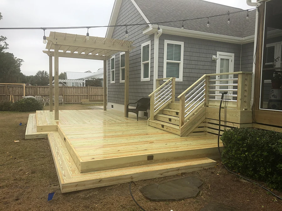 Backyard wood deck design with pergola and wooden fence