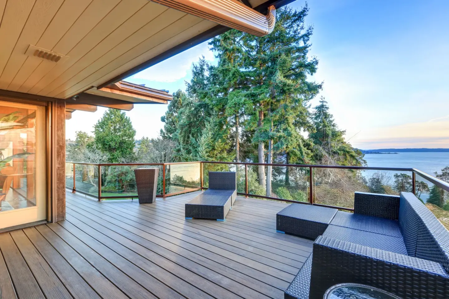 Commercial deck with glass railing and furniture with trees on the background