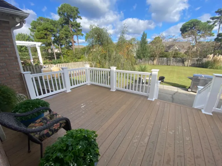 Composite hard wood deck with white metal railing featuring trees on the background