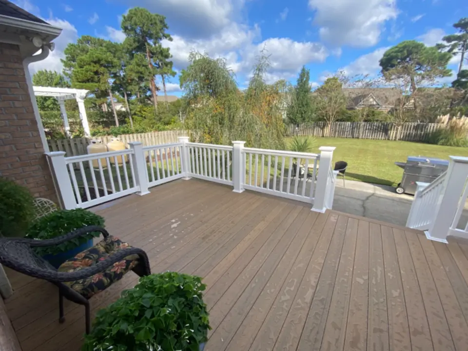 Composite hard wood deck with white metal railing featuring trees on the background