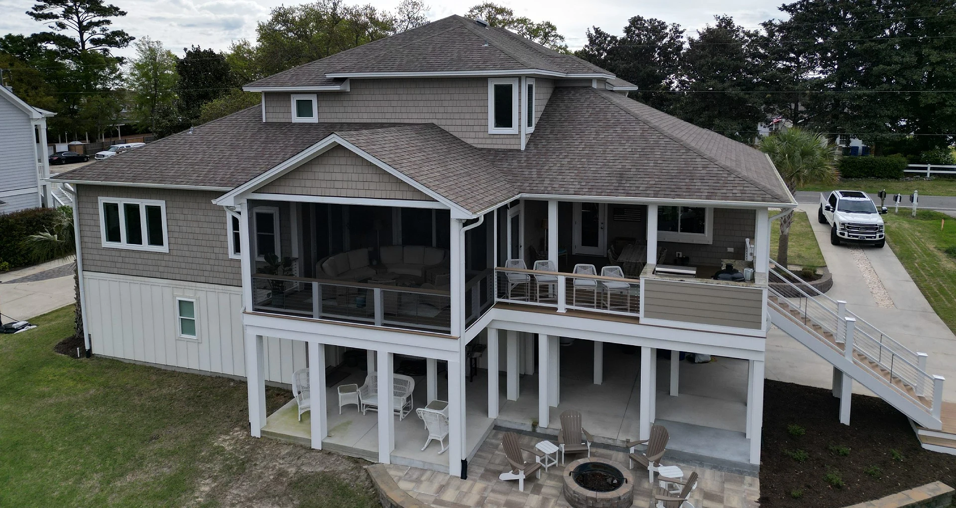 Covered backyard deck area with screened porch and outdoor firepit