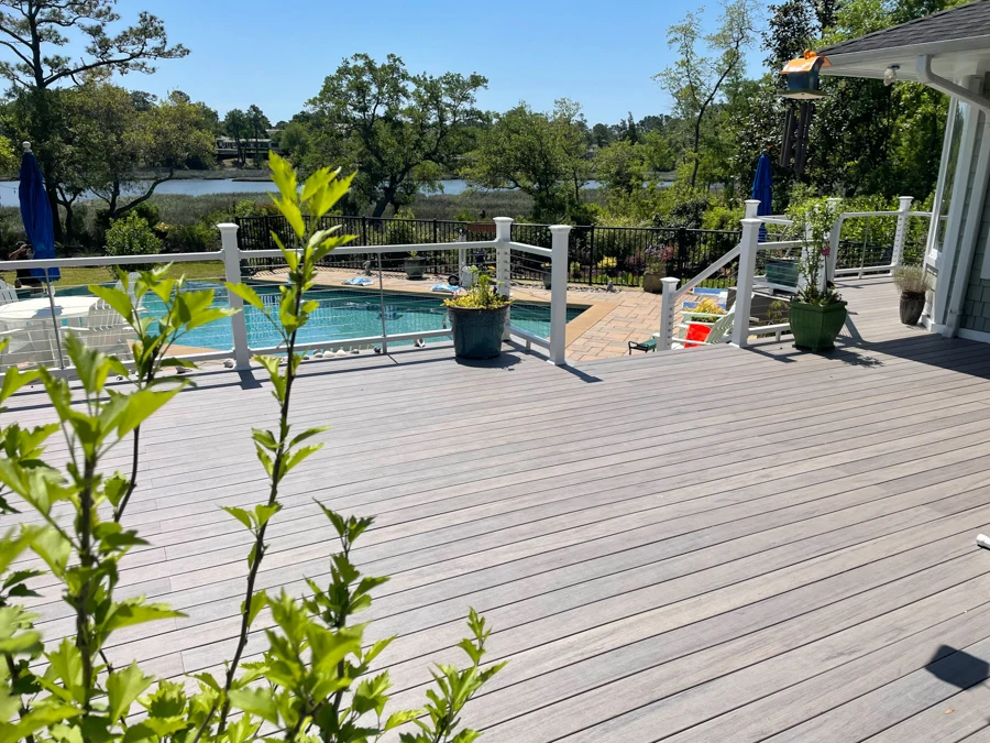 Poolside wooden deck installation with wire railing featuring overlooking nature view