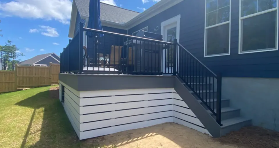 Residential deck with skirting and metal black railing with outdoor kitchen